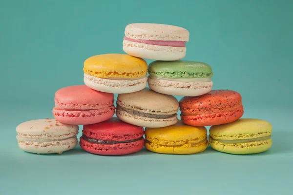 Pile of colorful macaroons stacked up like a tower in blue turquoise pastel isolated background