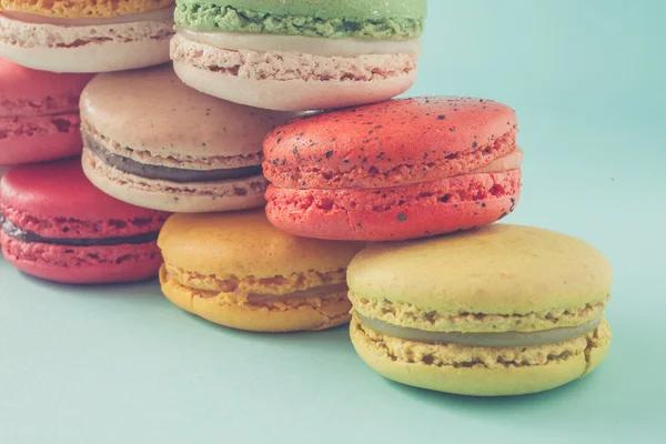 Pile of colorful macaroons stacked up like a tower in turquose pastel isolated background (Selective focus) - Closeup