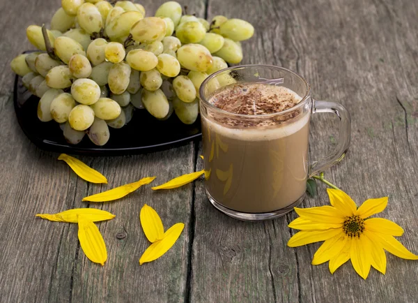 Plate with grapes, a cappuccino, a yellow flower and yellow peta