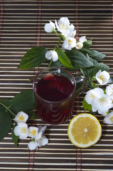 Glass of red tea, nearby lemon and flower