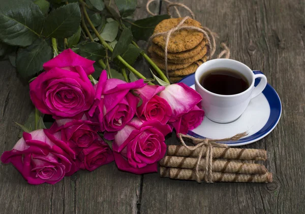 Cup of coffee, cookies and bouquet of scarlet roses