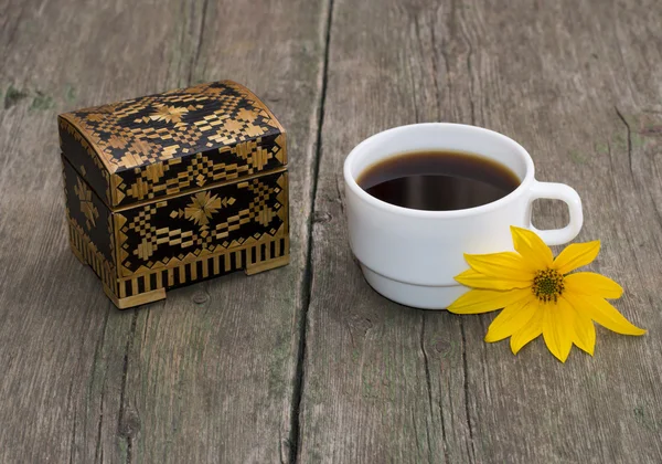 The cup of coffee decorated with a yellow flower and casket, sti