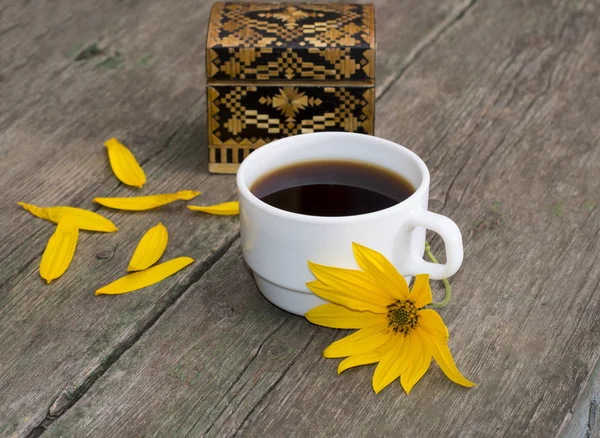 Casket, petals, yellow flower and coffee, on a wooden table, a s