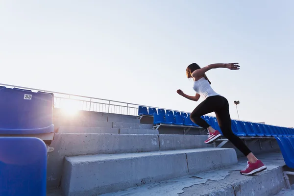 Young sportswoman in sportswear running upstairs on a stadium during her training success and speed concept