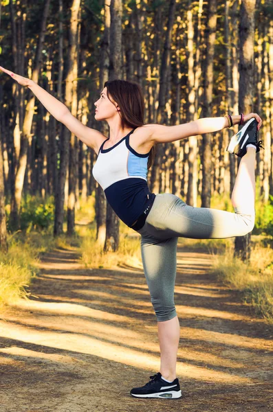 Woman in dancer position in forest landscape