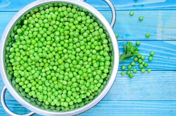 Fresh raw baby peas in small colander