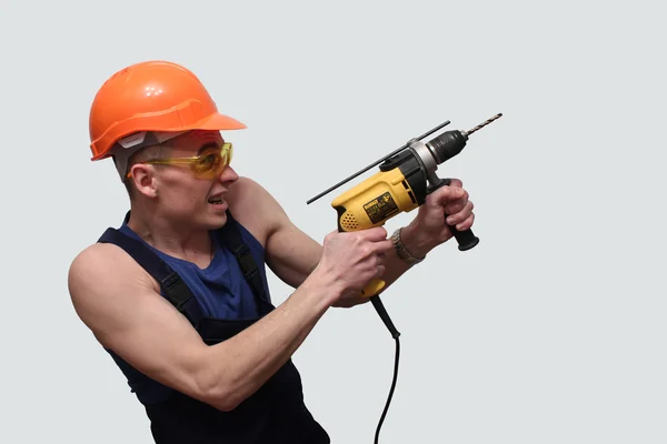 Portrait of a young, sexy man with a drill and a helmet