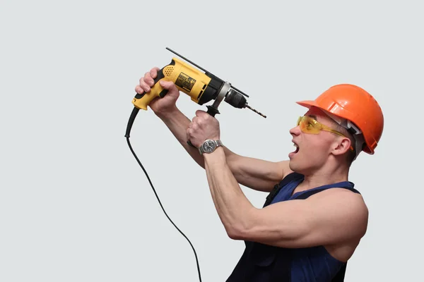 Portrait of a young, sexy man with a drill and a helmet