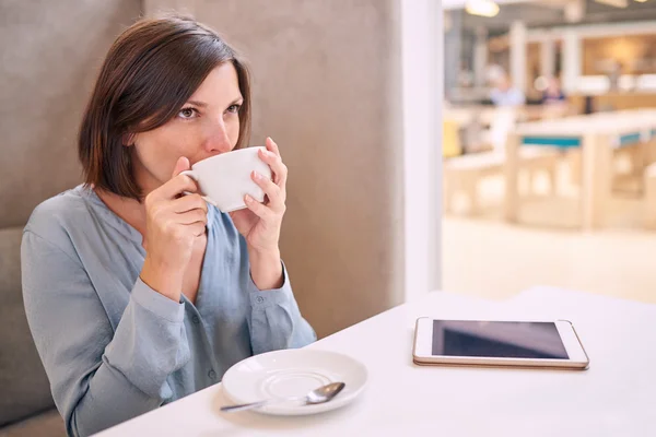 Casual well dressed woman taking a sip of her coffee