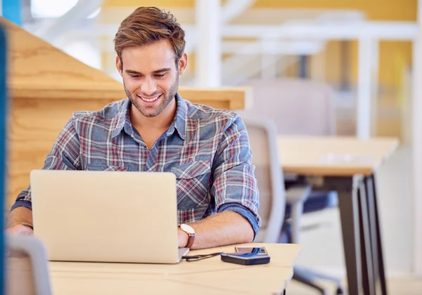 Adult man smiling while he works on his laptop