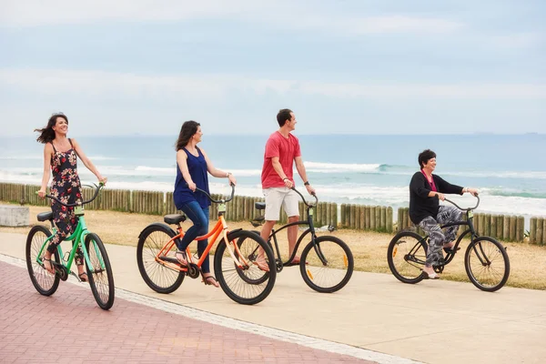 Happy healthy family riding bicycles along the seaside