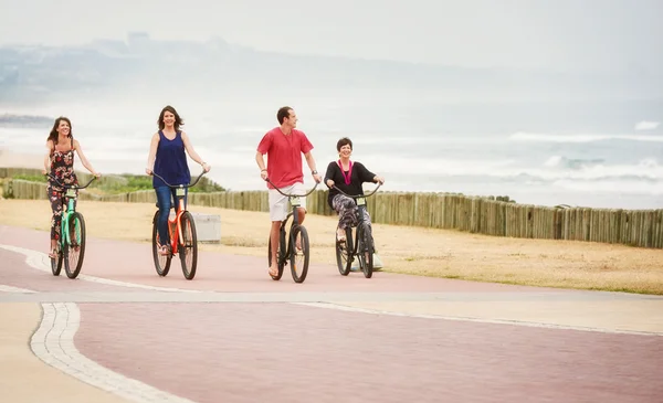 Happy healthy family riding bicycles along the seaside