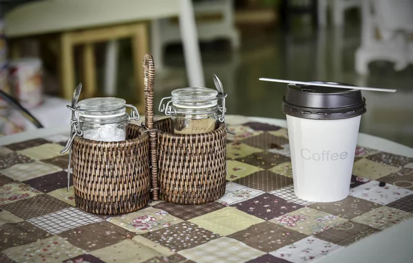 Bottle of sugar store in bamboo basket and paper coffee cup on