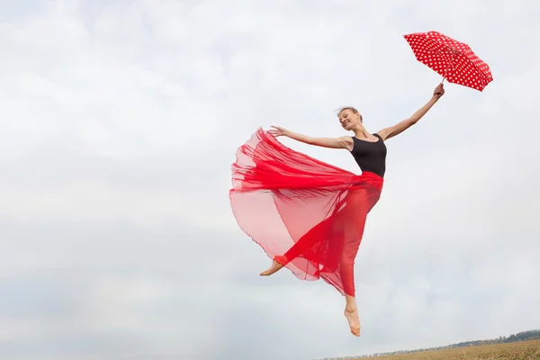 Young Woman Flying in the Sky with Red Umbrella