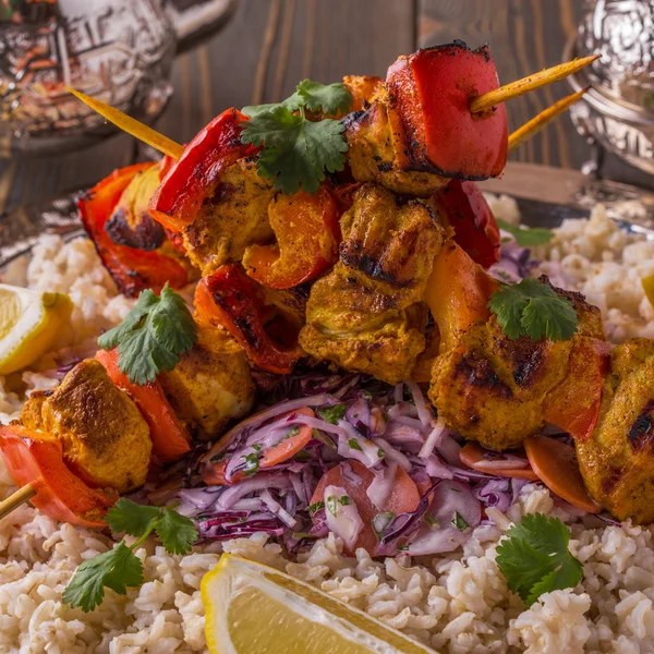 Grilled chicken and vegetable kebabs served with rice and salad.