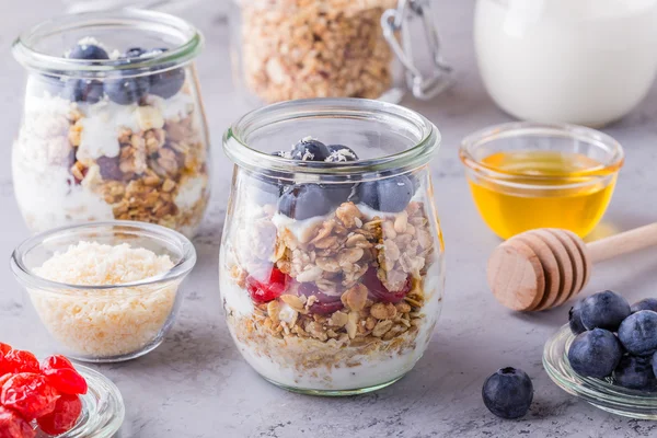 Glass jars of oat flakes with  fruit, yogurt and honey.