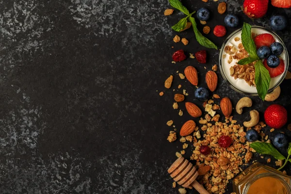 Tasty ingredients (granola, honey, berries, yogurt and nuts) for