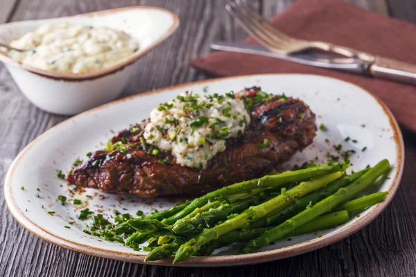 Steak with blue cheese sauce served with asparagus.