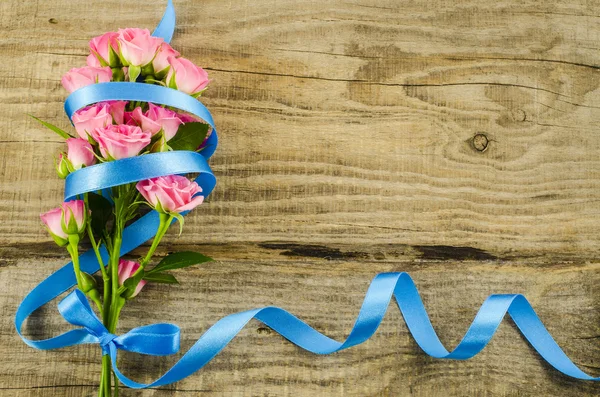 Empty wooden background with colorful flowers and blue ribbon