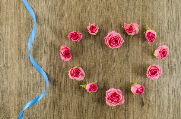 Heart shaped rose flower and ribbon on wooden background