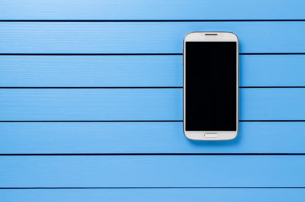 White mobile phone with black screen on wooden background