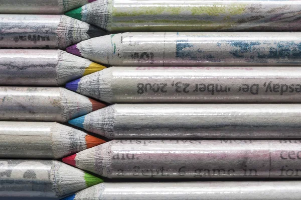 Several colored pencils facing each other, recycled paper