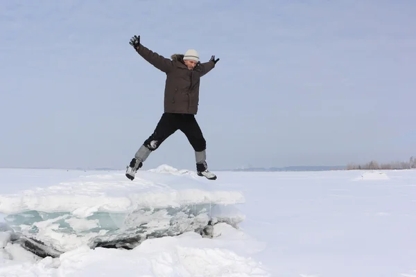 The man with a beard in a gray cap jumping from an block of ice