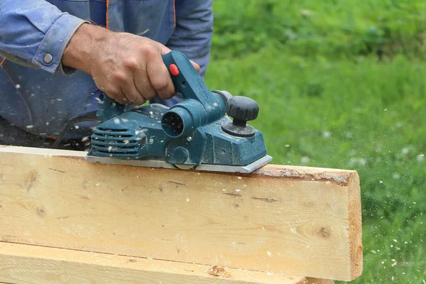 The male hand processes a wooden board an electric jointer plane