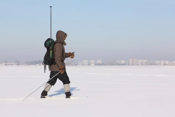 The man the traveler with a backpack skiing on snow of the river