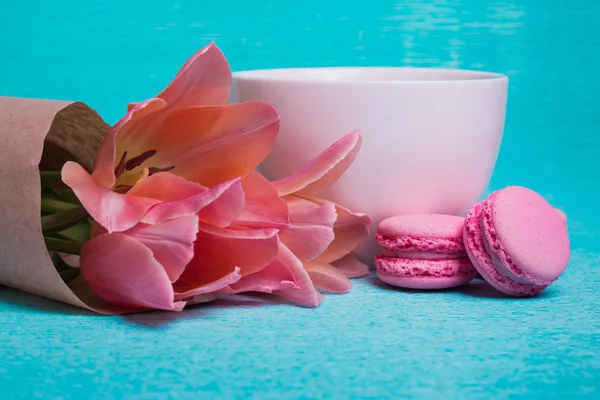 Three pink tulips, a cup of coffee and three pink macaroons