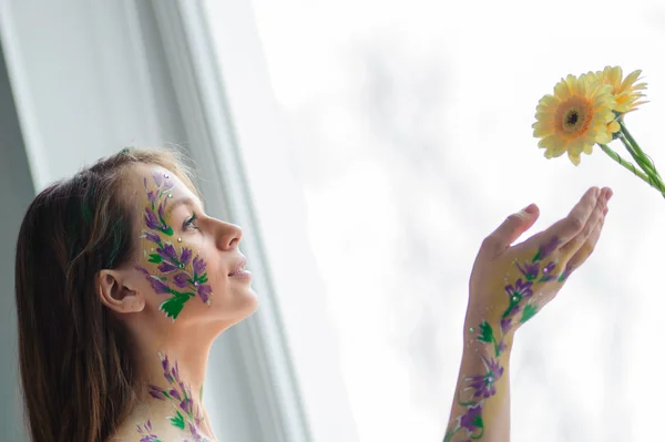 Girl with flower bodyart and sunflowers bouquet