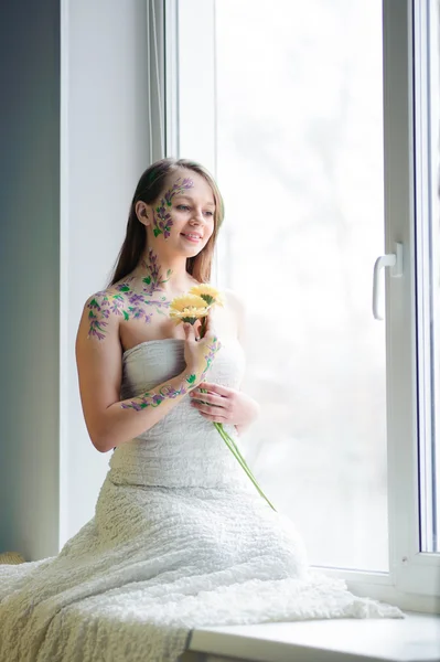 Girl with flower bodyart and sunflowers bouquet and wreath