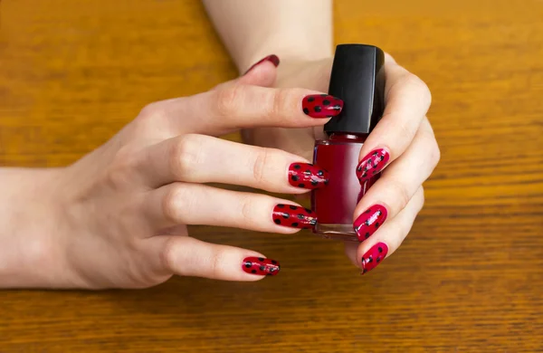 Hands girls holding a bottle of red nail Polish