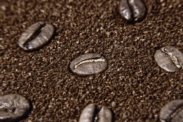 Macro of grains coffee over ground coffee background