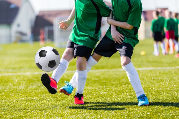 Young boys kicking soccer football on the sports field.