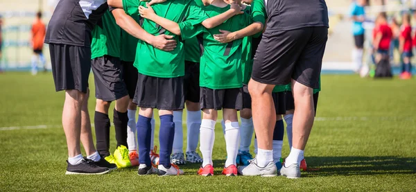 Football soccer match for children. Coach giving young soccer team instructions. Youth soccer team together before final game. Football match for children. Boys group shout team, gathering. Coach briefing. Soccer football background.