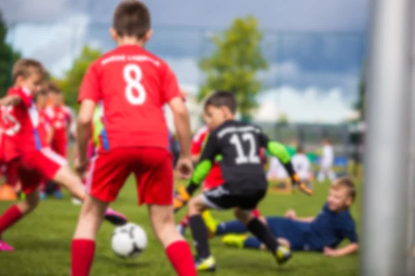 Blurred sport soccer football background. Young boys playing football match. children\'s soccer match. Red against black team.