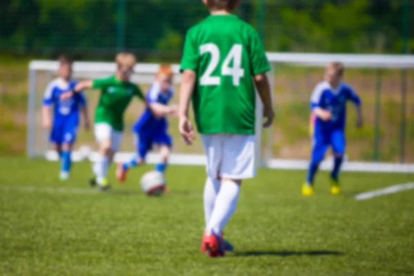 Blurred sport soccer football background. Young boys playing football match. Blue against green team.