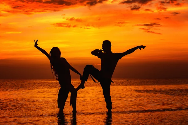 Silhoette of hot dancing couple at golden tropical sea sunset background.