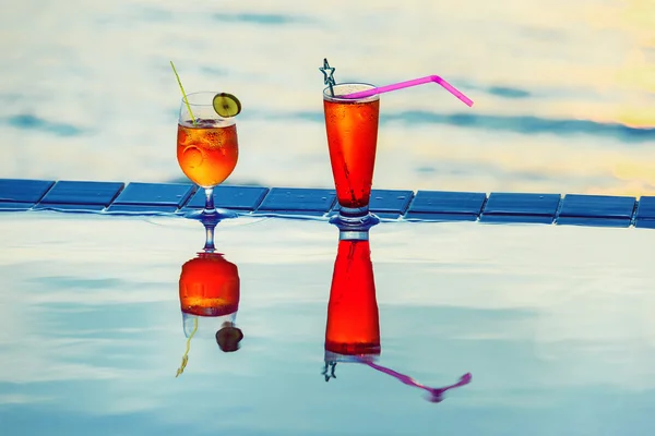 Colorful closeup image of tasty red cocktails at swimming pool at blue sea background.