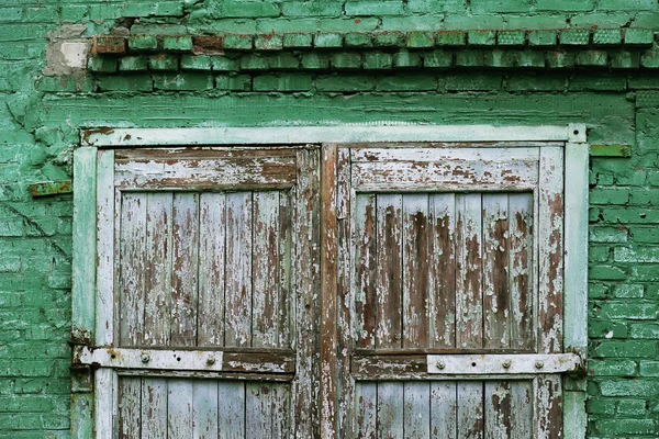 A wooden vintage scaled door at green bricks wall background.