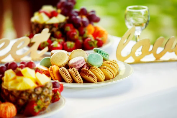Closeup image of fresh fruits and berries and cookies at a white table background.