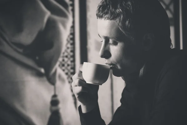 Closeup black and white portrait of man drinking coffee in vintage style.