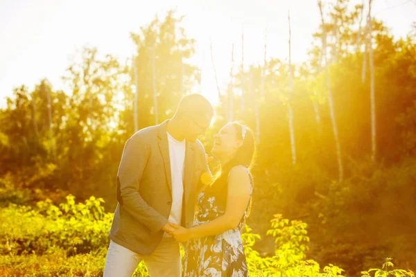 Portrait of happy couple kissing at natural sunset summer bright background.