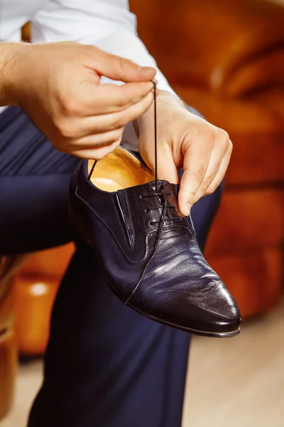 Close up image of a man who is preparing for his workday and tying a shoe lace.