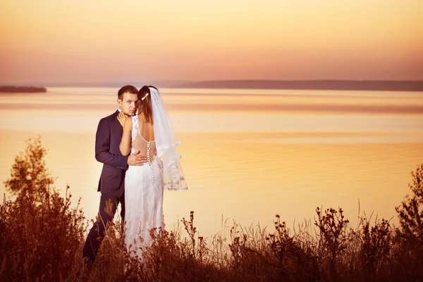 Beautiful couple is embracing at golden summer sea sunset background.