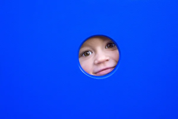 Little kid playing peek-a-boo on a playground