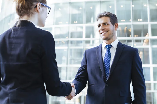 Two young business people shaking hands