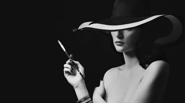 Black and white portrait of a girl in a hat with a cigar