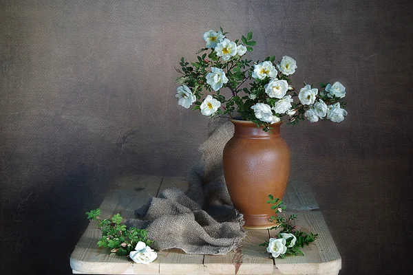 White roses in a bouquet on a brown background .